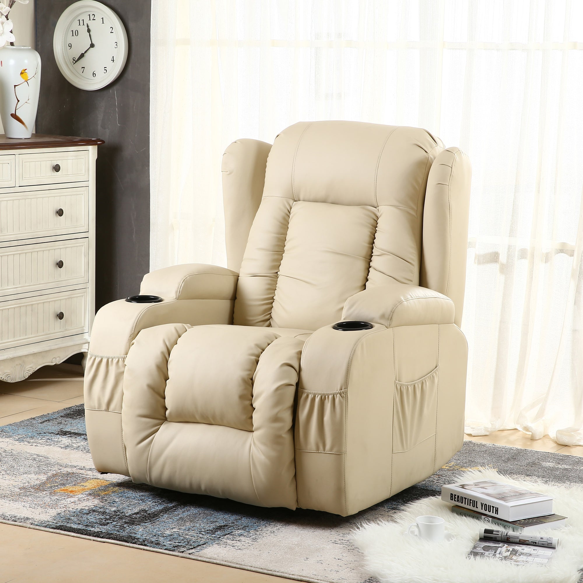 Cream leather rise recliner with vertical stitching on the backrest, padded armrests, cup holders, and front and side pockets, placed in a cosy living room setting with soft lighting and a patterned rug.
