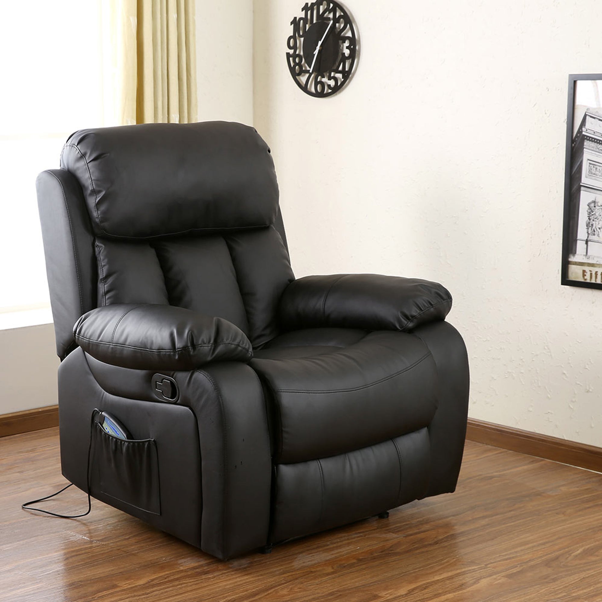 Black leather manual recliner with padded armrests and a cushioned backrest featuring vertical stitching details, positioned in a living room with wood flooring.