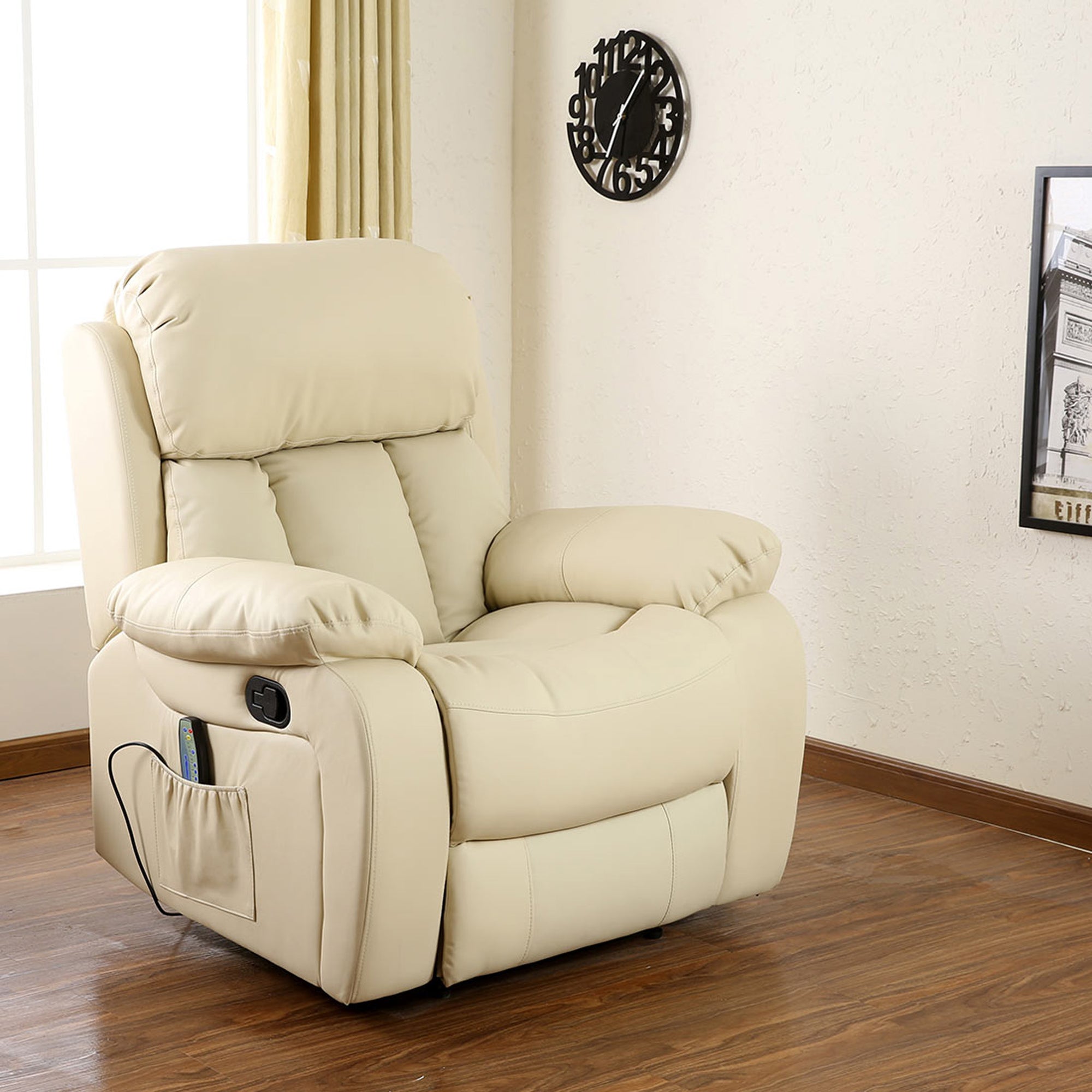 Cream leather manual recliner with padded armrests and a cushioned backrest featuring vertical stitching, positioned in a living room with wood flooring and wall decor. A side pocket holds a remote control.