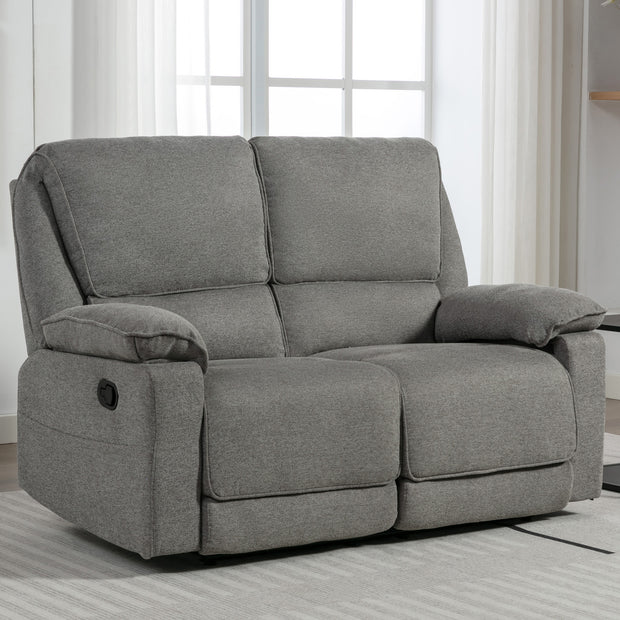 Grey fabric manual reclining two-seater sofa with padded armrests, placed on a light-coloured rug in a living room near large windows.