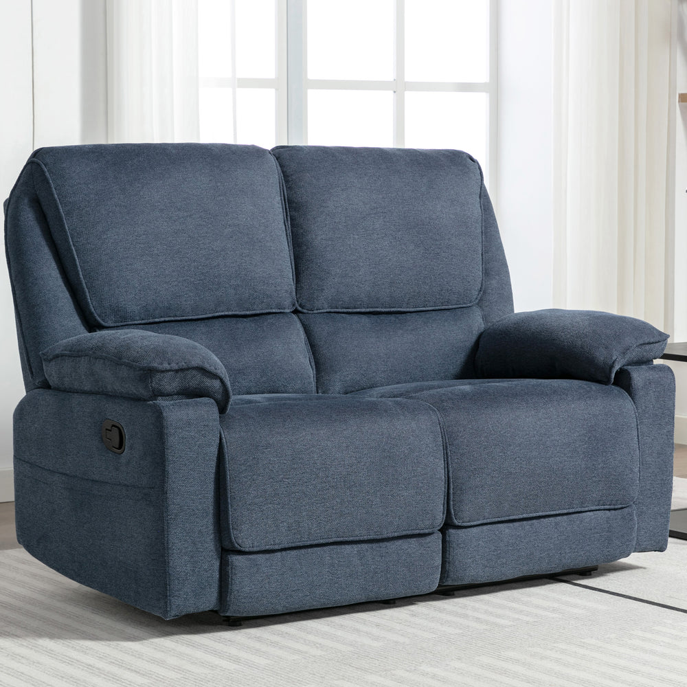 Blue fabric manual reclining two-seater sofa with padded armrests, placed on a light-coloured rug in a living room near large windows.