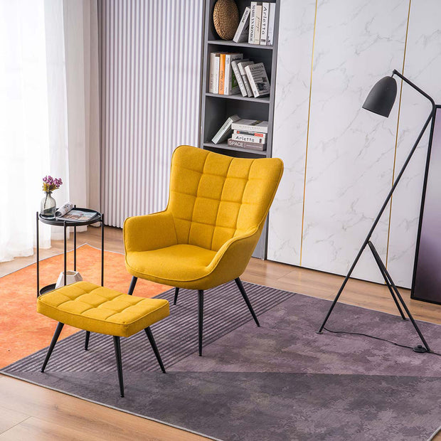 A yellow linen accent chair with a matching footstool, both with black tapered legs, positioned in a room with a floor lamp, side table, and bookshelf.