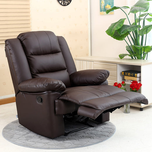 A dark brown manual recliner chair in a semi-reclined position, set on a grey circular rug next to a side table with books and plants, in a cosy room.