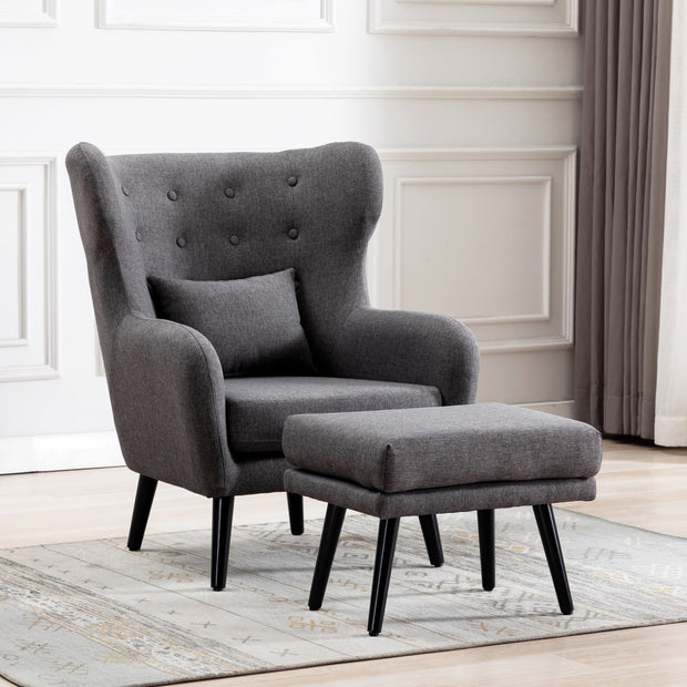 Grey linen accent wingback chair with tufted buttons, paired with a matching footstool, set on a grey patterned rug against a white panelled wall.