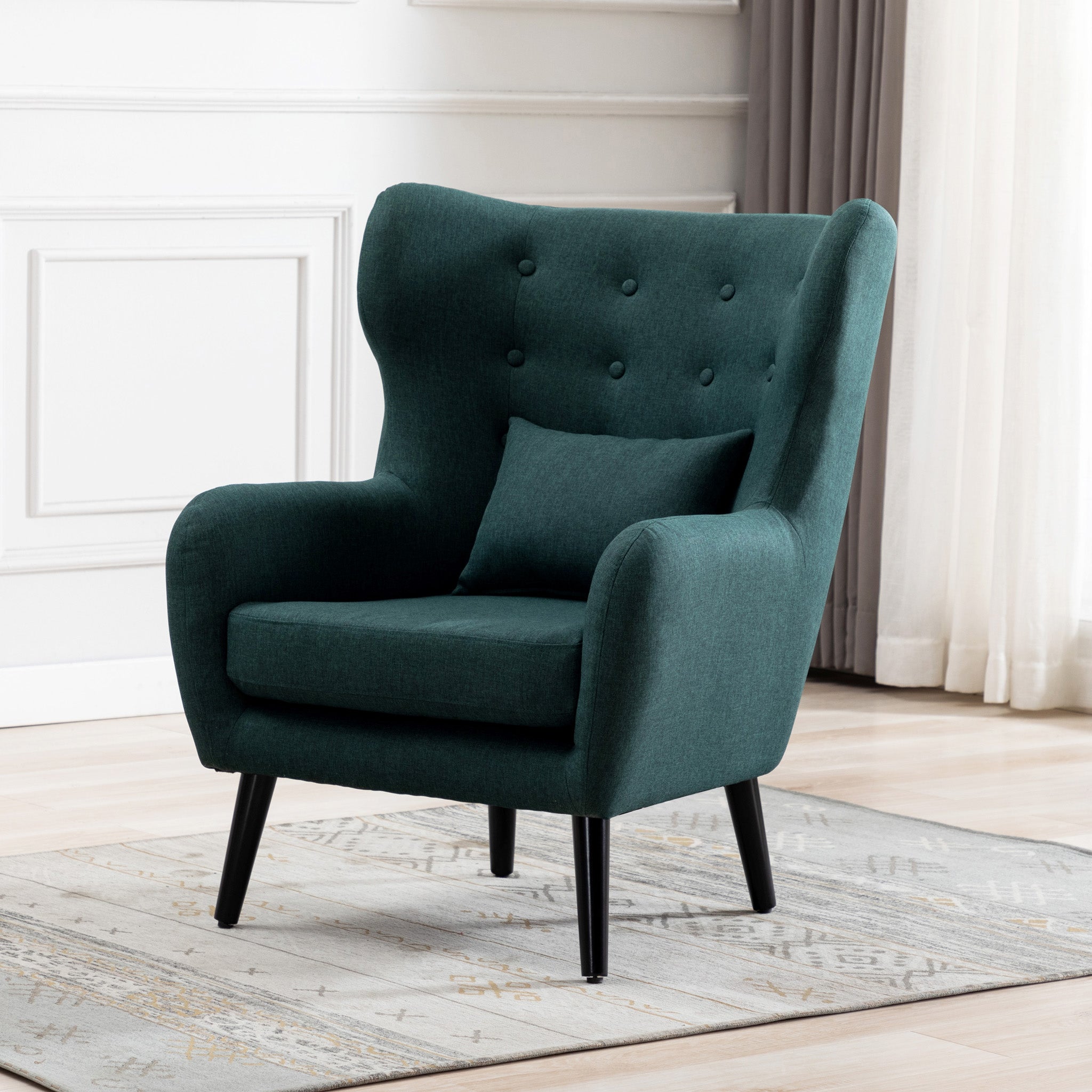 Green linen accent wingback chair with tufted buttons, set on a grey patterned rug against a white panelled wall.