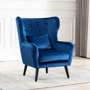 Blue velvet accent wingback chair with tufted buttons, set on a grey patterned rug against a white panelled wall.