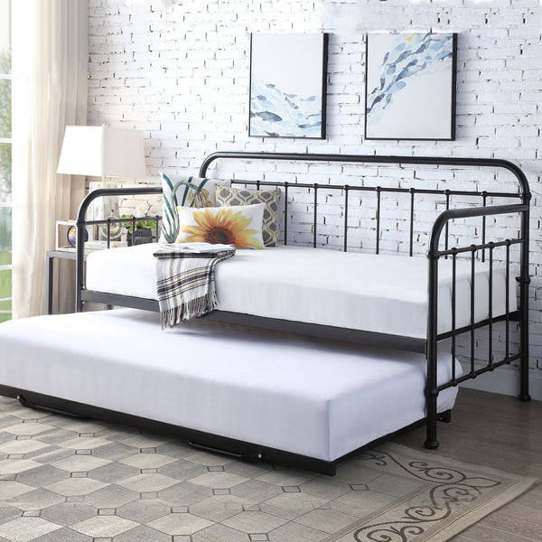 Black metal daybed with a pull-out trundle, white linens, and decorative pillows, set against a white brick wall.