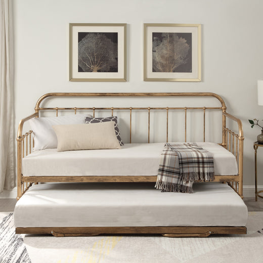 A white bedroom featuring a brass metal day bed with a trundle, white bedding, decorative pillows, and a plaid throw blanket. Two framed tree artworks hang above.