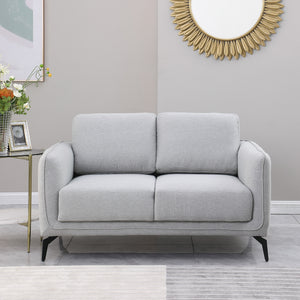 Light grey upholstered sofa with black metal legs in a grey living room, featuring a round sunburst mirror and a side table with flowers.