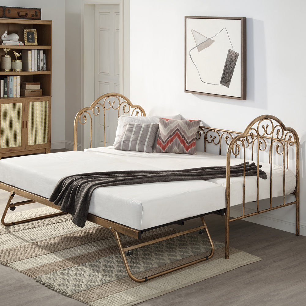  A brass metal day bed with an extended trundle is adorned with white bedding, decorative pillows, and a grey throw blanket. A geometric painting hangs above the bed. 