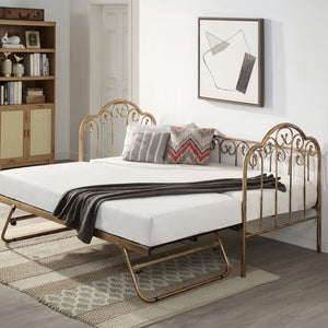 A brass metal day bed with an extended trundle is adorned with white bedding, decorative pillows, and a grey throw blanket. A geometric painting hangs above the bed. 