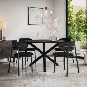 Black dining table with crossed pedestal base, surrounded by four dark upholstered chairs