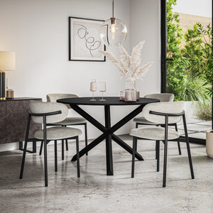 Black dining table with a crossed base and four grey upholstered chairs, shown in a dining room