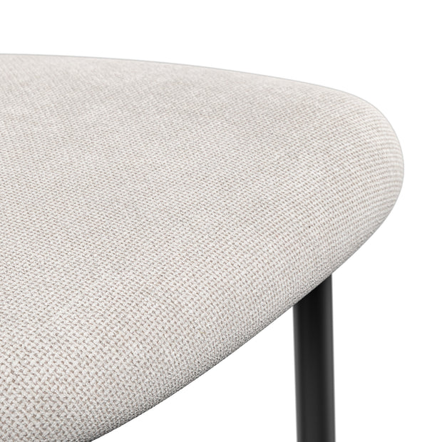 Close-up of a beige chair seat with a tightly woven texture and rounded edge