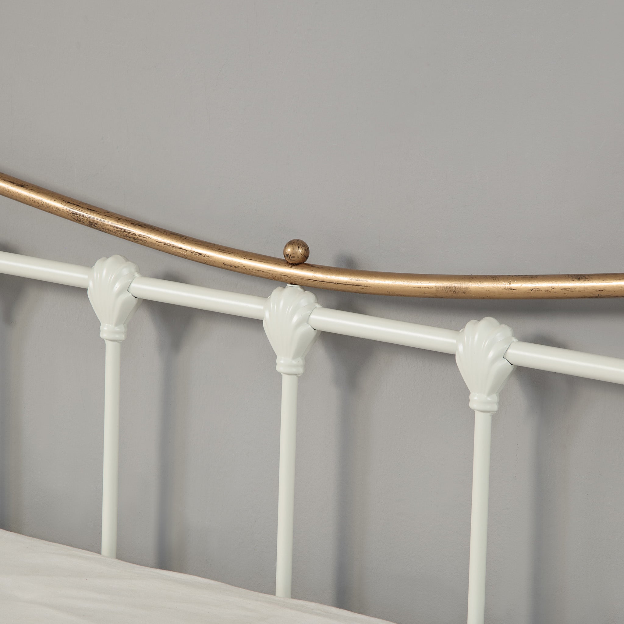 Close up view of a white and brass metal headboard.