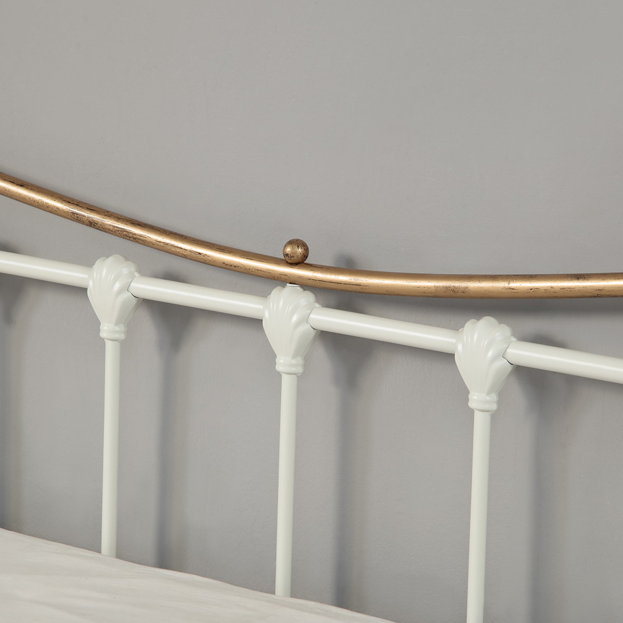 Close up view of a white and brass metal headboard.