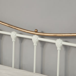 Close up view of a white and brass metal headboard.